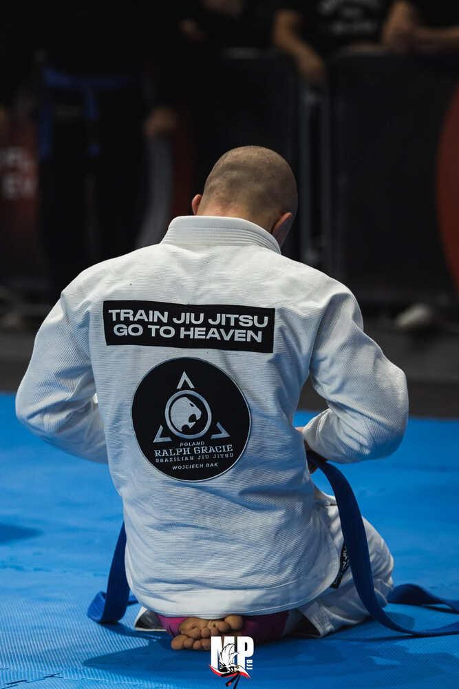 Patryk tying his blue belt on the competition mat